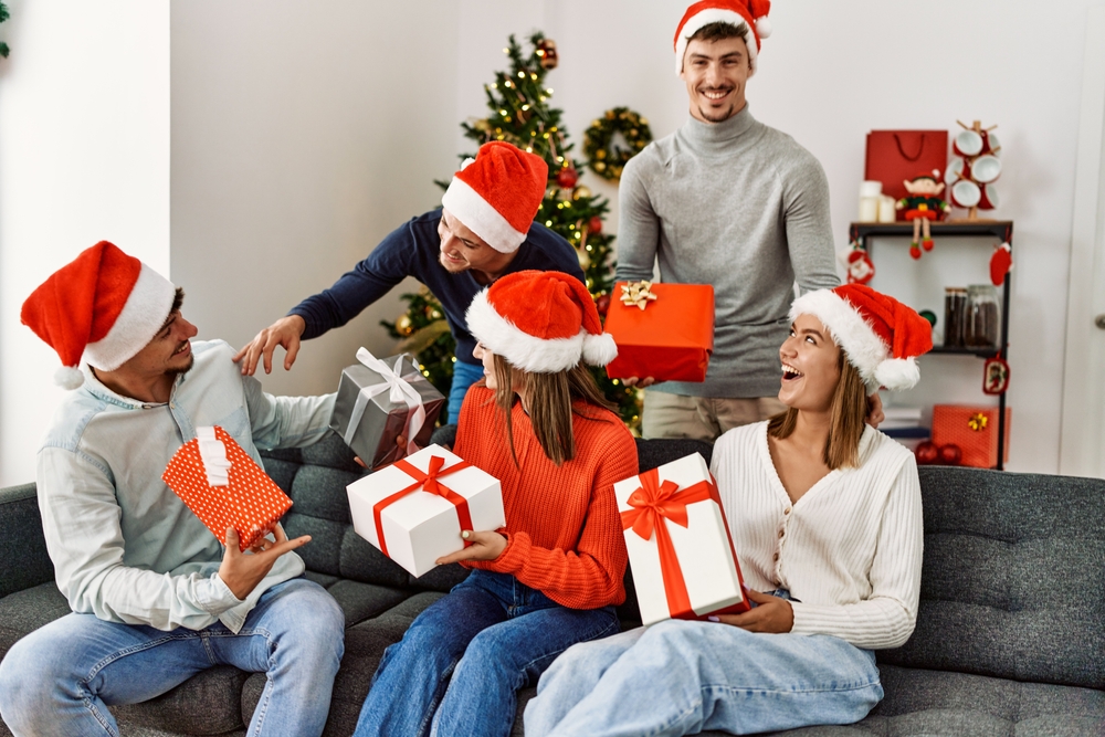 Group of young people giving christmas gift at home.