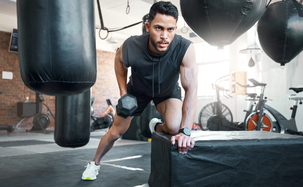 Shot of a sporty young man exercising with a dumbbell in a gym.