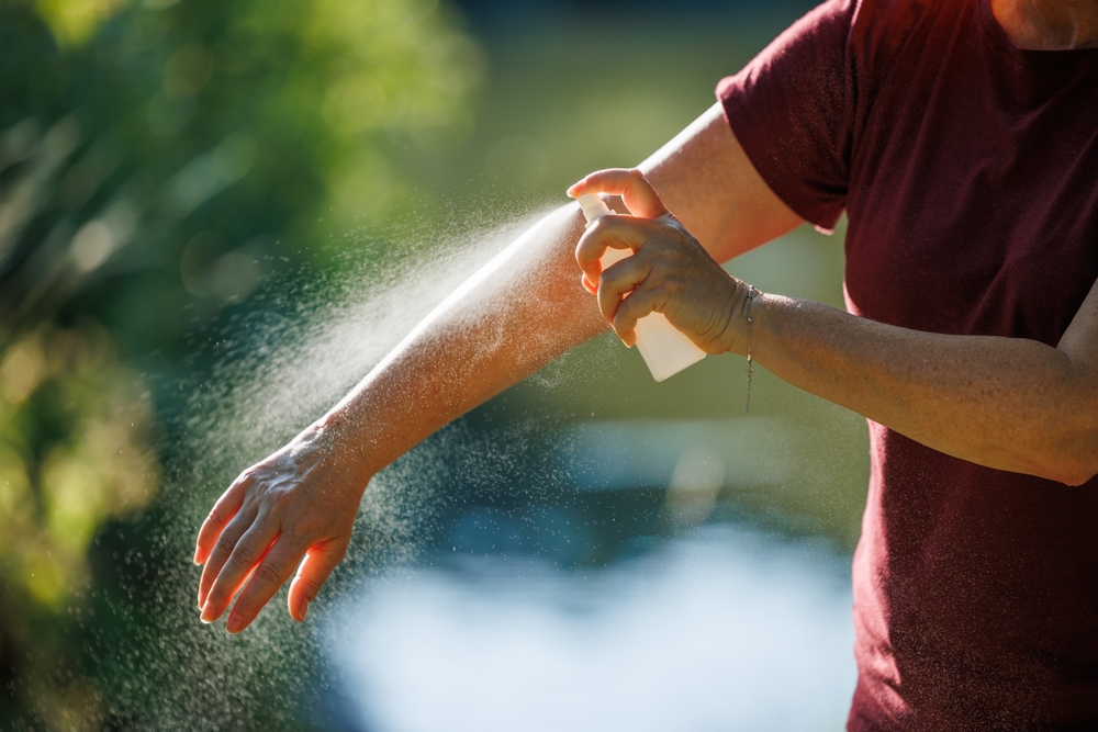 Woman applying insect repellent on her arm outdoors. Skin protection against tick and mosquito bite