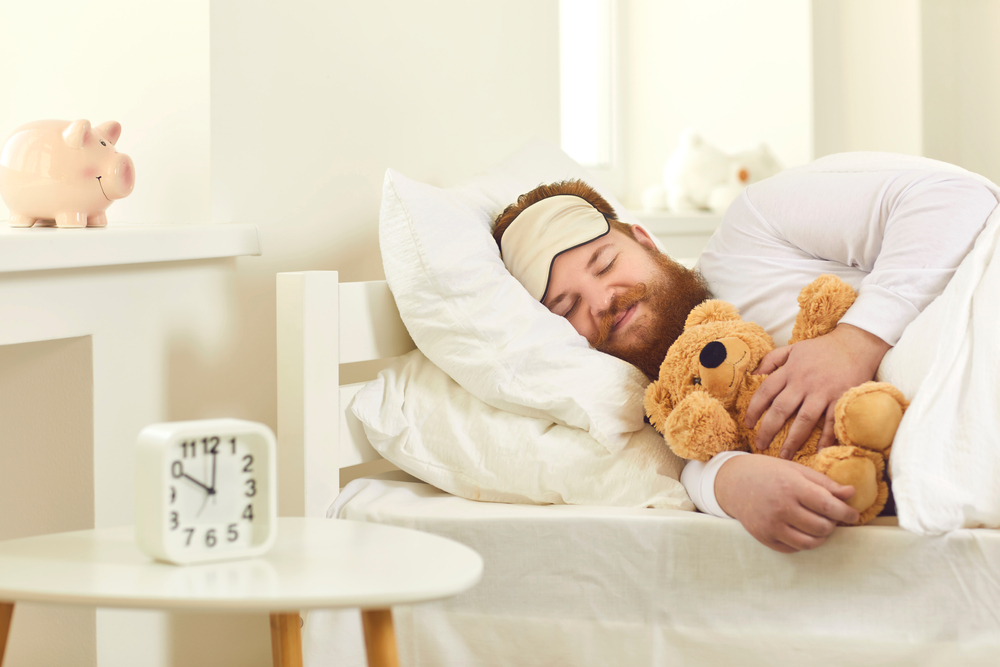 man relaxing in bed with teddy bear